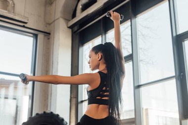 Spor salonundaki halterleri tutan esnek kadınların arka plan görüntüsü.