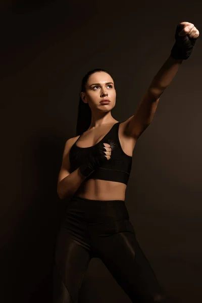 Hermosa deportista en guantes deportivos con la mano extendida aislada en negro - foto de stock