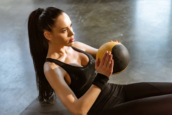 Женщина, держащая мяч и делающая абс в спортцентре — стоковое фото