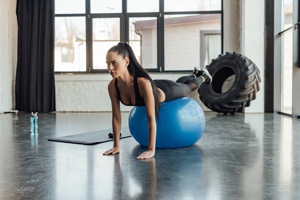 Brunette sportive s'entraînant sur le ballon de fitness dans un centre sportif — Photo de stock