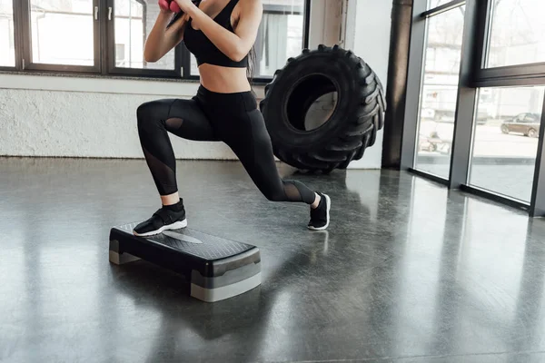 Cropped view of sportswoman working out on step platform in gym — Stock Photo