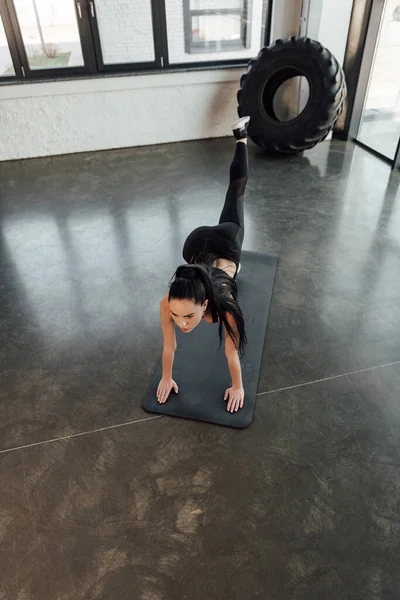 Hochwinkelaufnahme einer Sportlerin, die auf allen Vieren auf einer Fitnessmatte im Fitnessstudio trainiert — Stockfoto