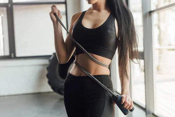 Cropped view of sportswoman with skipping rope in gym — Stock Photo