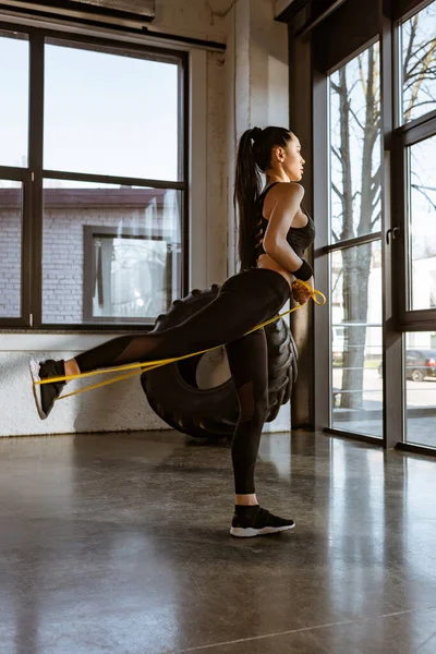 Seitenansicht einer Sportlerin, die im Fitnessstudio mit Widerstandsband trainiert — Stockfoto