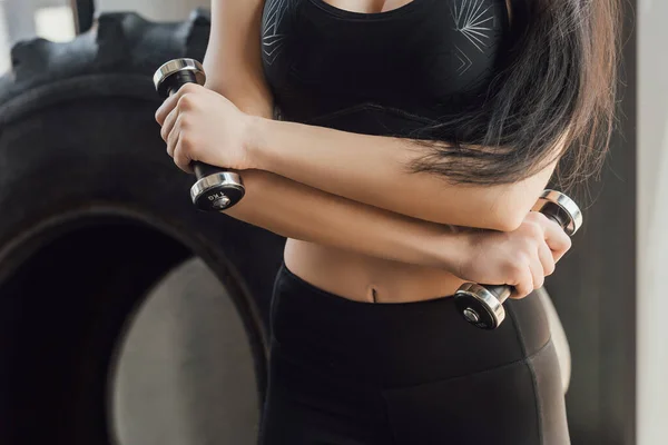 Cropped view of sportswoman holding dumbbells in sports center — Stock Photo