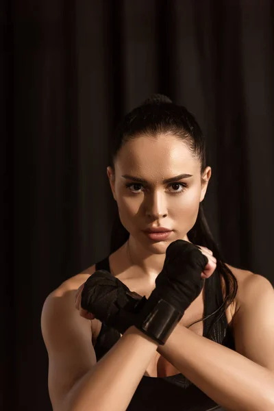 Sportswoman in fighting position looking at camera on black — Stock Photo