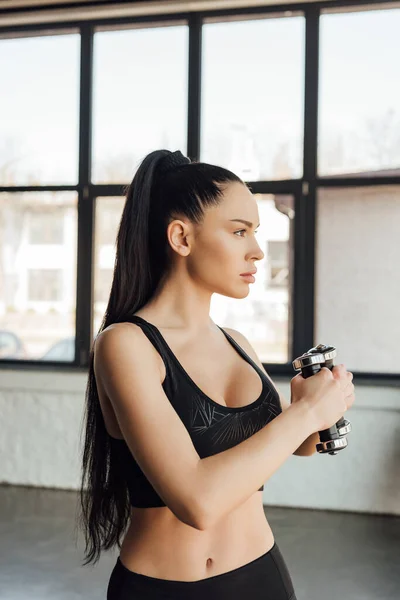 Attractive sportswoman working out with dumbbells in sports center — Stock Photo