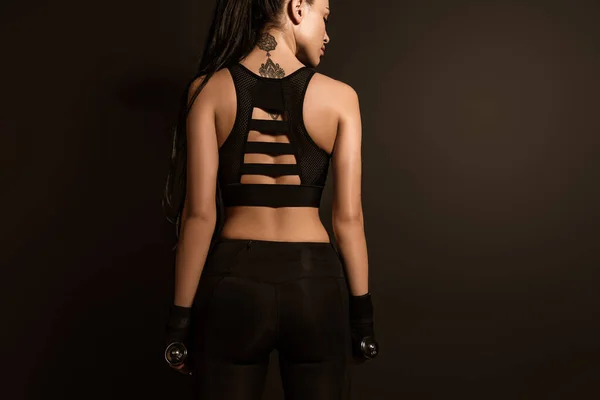 Вид сзади спортсменки с гантелями, изолированными на черном — стоковое фото