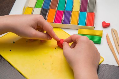 Çocuk renkli plastikten heykel yapmayı öğreniyor.