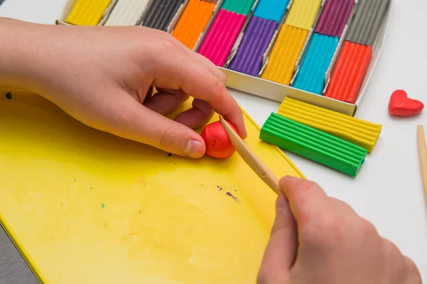 Çocuk renkli plastikten heykel yapmayı öğreniyor.