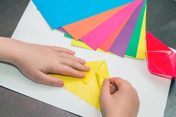 Çocuk renkli kağıtlardan origami yapmayı öğreniyor