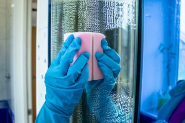 Kız özel bir sıvı ve süngerle aynayı temizliyor. Temizlik ürünleriyle banyoyu temizlemek. Temizlik