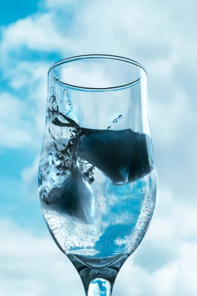 Glas Water Voor Blauwe Bewolkte Lucht Ijsblokjes Vallen Het Water — Stockfoto