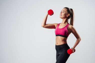 Dambıllarla Egzersiz Yapan Kız Gri Arkaplan Üzerinde Kameranın Önünde Duruyor