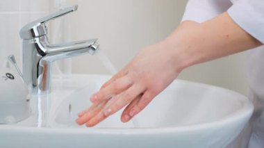 Kadın doktoru düzgünce kapatın ve ellerini sabun köpüğüyle iyice yıkayın. Tıbbi uzman her parmağı yıkar, hastanede ellerini dezenfekte eder.