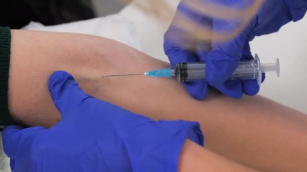 Closeup of nurse hands inserts needle into vein. A medical worker wearing blue protective gloves is going to take blood from a patients vein for analysis. Donating blood, saving lives — Stock Video