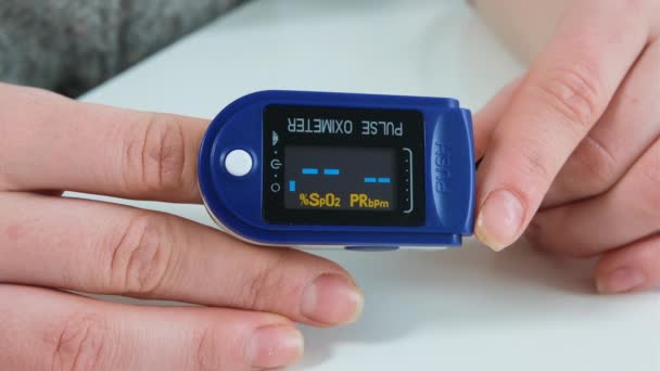 A nő kék pulzusmérőt tart a kezében. A monitor oxigéntelítettséget mutat a vérben és pulzusszámot a betegben. Közelről. — Stock videók