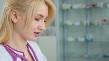 Klinikteki beyaz önlüklü genç bayanı dizüstü bilgisayar kullanarak not yazarken yakın plan çek. Sıhhiye laptopa bakıyor yanlış teşhis hakkında veri analiz ediyor ve bir çözüm buluyor.