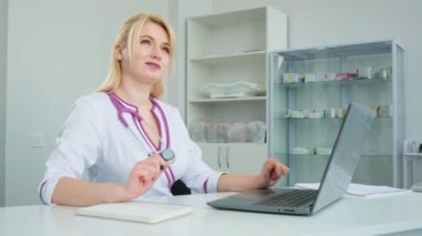 Beyaz, yakışıklı bir doktor kabinede oturuyor ve tıp dergisine not alıyor. Kadın doktor teşhisi düşünür ve bir reçete yazar.