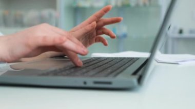 Beyaz bornoz giyen doktorların ellerini yakından çek. Kadın taşınabilir bir dizüstü bilgisayarın klavyesine metin yazdırıyor.