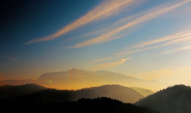 Dağ tepeleri olan çok güzel bir manzara. Gökyüzü, bulutlar ve sis renkli. Sis derin bir perspektif veriyor..