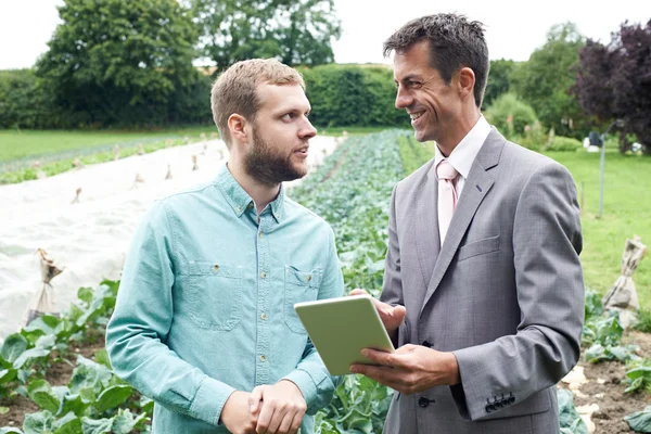 Zakenman met behulp van digitale Tablet tijdens ontmoeting met boer In F — Stockfoto