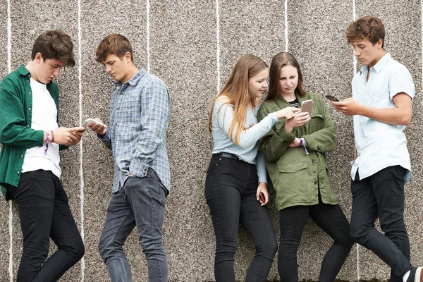 Grupa nastolatków dzielenie tekstu wiadomości na telefony komórkowe — Zdjęcie stockowe