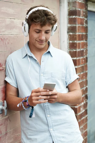Adolescente niño usando auriculares y escuchando música en urbano S — Foto de Stock
