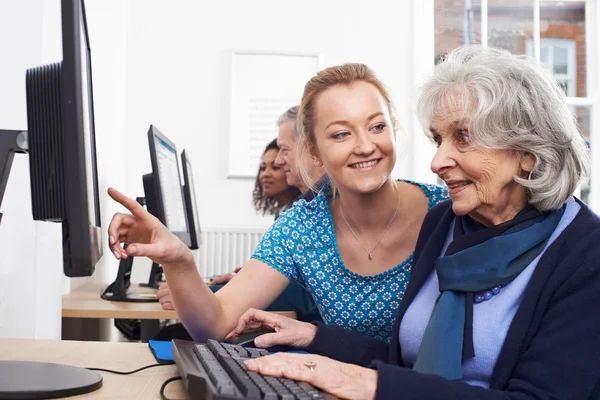 Репетитор, помогающий пожилой женщине в компьютерном классе — стоковое фото