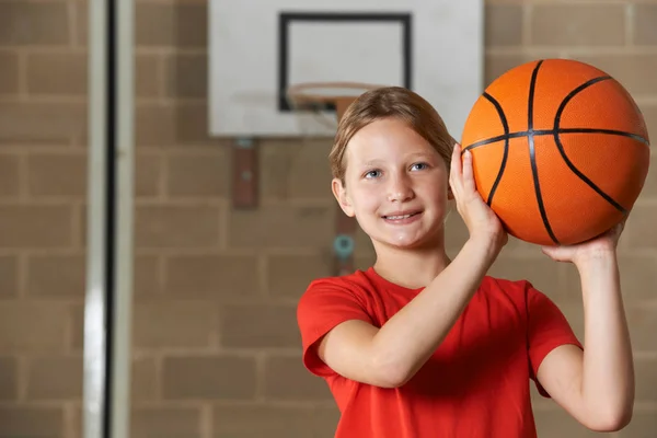 Mädchen schießt Basketball in Schulsporthalle — Stockfoto