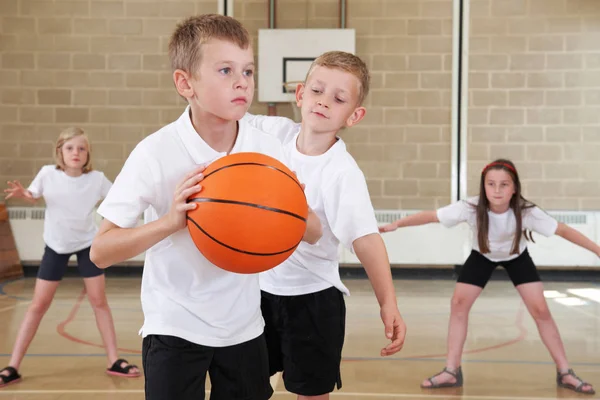 Uczniowie szkoły podstawowej gry w koszykówkę w siłowni — Zdjęcie stockowe