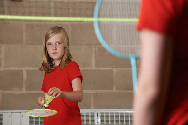 Две девочки играют в бадминтон в школьном спортзале — стоковое фото
