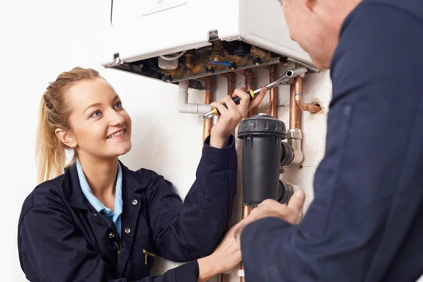 Vrouwelijke stagiair loodgieter werken aan centrale verwarming boiler — Stockfoto