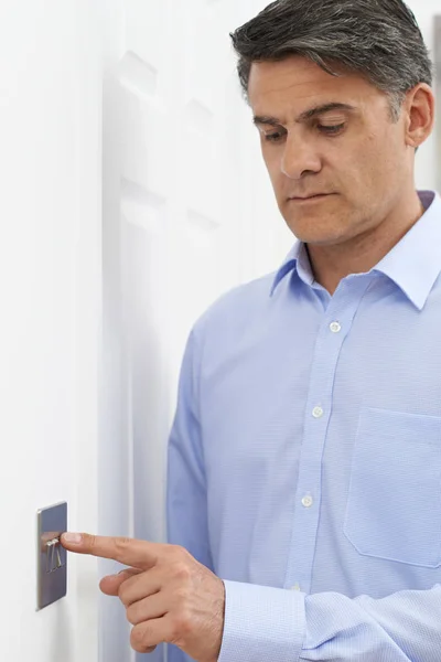 Mature Man Turning Off Light Switch At Home — Stock Photo, Image