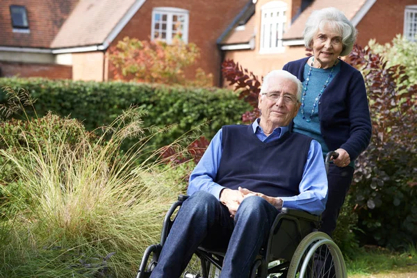 Starszy człowiek, pchanych przez żonę na wózku inwalidzkim — Zdjęcie stockowe