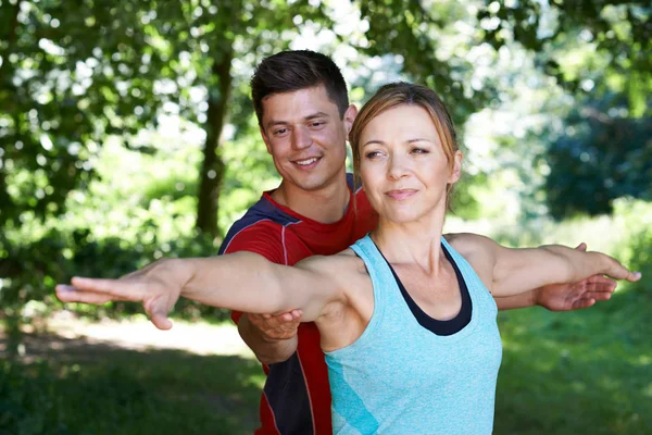 Mujer madura con entrenador de yoga en el parque — Foto de Stock