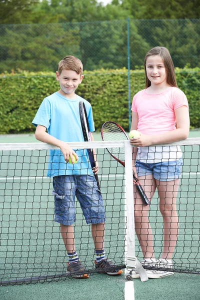Портрет мальчика и девочки, играющих в теннис вместе — стоковое фото