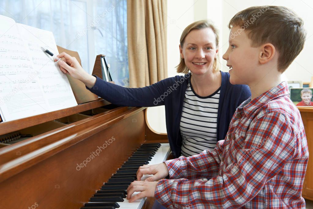 Boy With Music Teacher Having Lesson At Piano