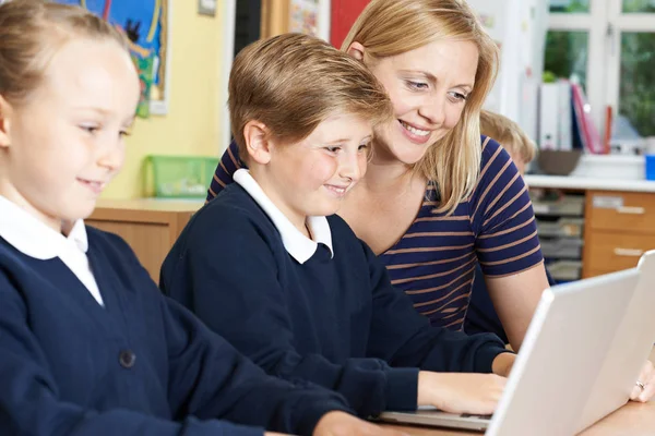 Enseignant aidant les élèves de l'école primaire en classe d'informatique — Photo