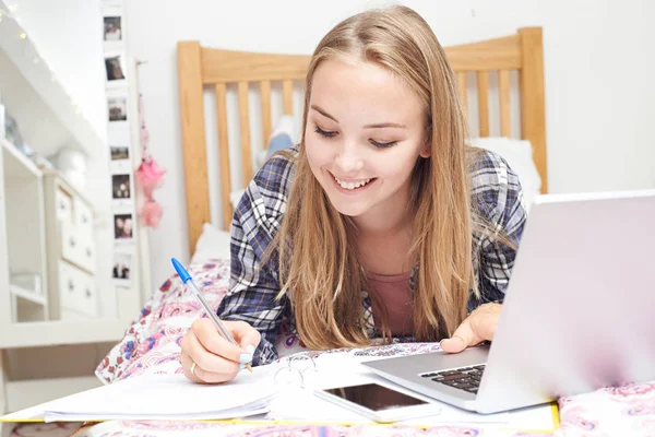 Adolescente chica usando el ordenador portátil para hacer la tarea en el dormitorio — Foto de Stock