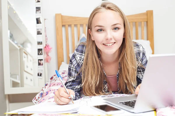 Adolescente chica usando el ordenador portátil para hacer la tarea en el dormitorio — Foto de Stock