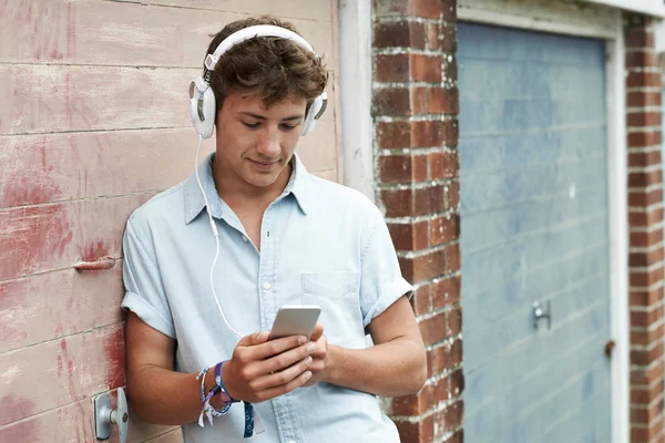 10 代の少年を着てヘッドフォンや都市 s で音楽を聴く — ストック写真