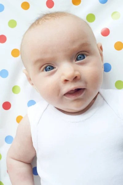 Visão aérea da menina do bebê que jaz no tapete colorido da mudança — Fotografia de Stock