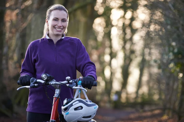 Mujer montando en bicicleta de montaña a través de bosques — Foto de Stock