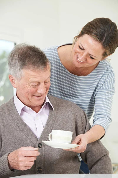 Adult Daughter Bringing Senior Father Hot Drink At Home — Stock Photo, Image