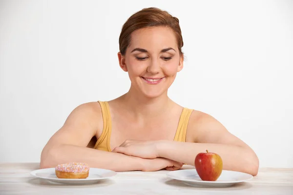 Jonge vrouw kiezen tussen donut en Cake voor Snack — Stockfoto