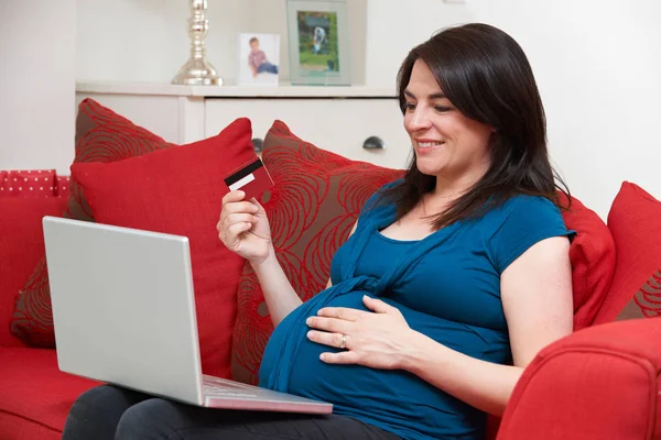 Zwangere vrouw zittend op de Bank creditcard gebruiken om te winkelen Online — Stockfoto