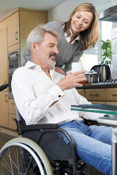 Femme amenant l'homme en fauteuil roulant boisson chaude à la maison — Photo