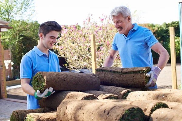 Paisajistas jardineros tendiendo césped para césped nuevo —  Fotos de Stock