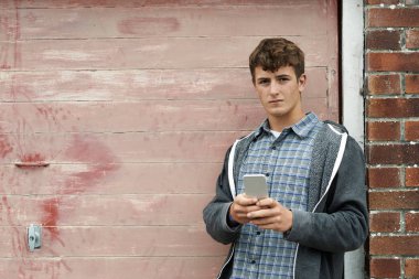 Kentsel ortamda cep telefonunda genç çocuk manifatura